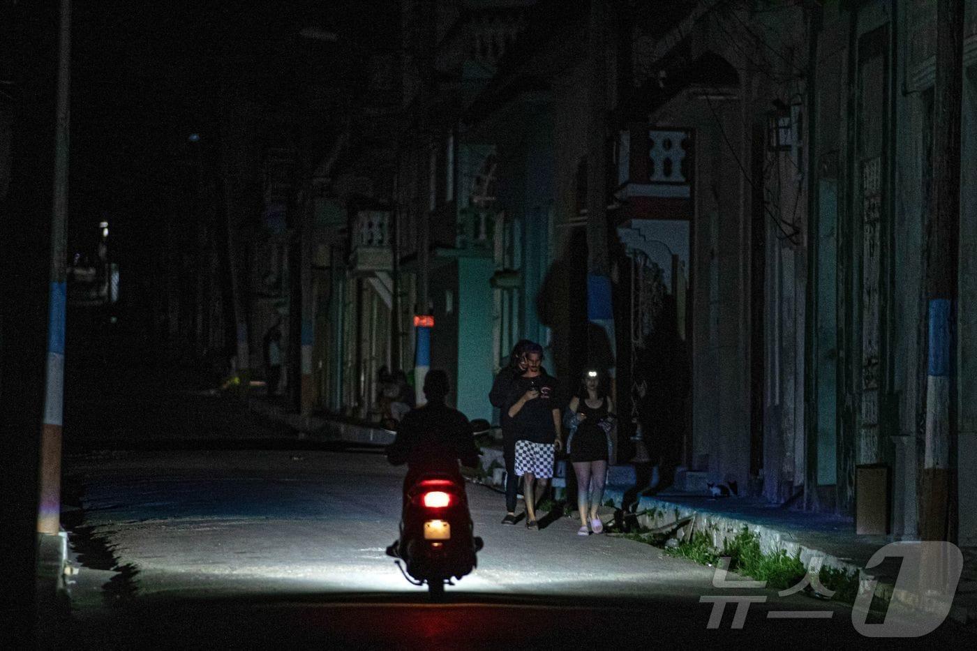 본문 이미지 - 6일(현지시간) 쿠바 마탄사스에서 정전으로 어두컴컴한 거리를 오토바이 운전자가 달리고 있다. 마탄사스는 쿠바에서 가장 심한 전력 부족에 시달리는 도시 중 하나로, 국가 최대 발전소 중 하나인 안토니오 구티에라스 화력 발전소가 있음에도 24시간 이상 전기가 끊기는 경우가 종종 발생한다. 2026.04.06. ⓒ AFP=뉴스1