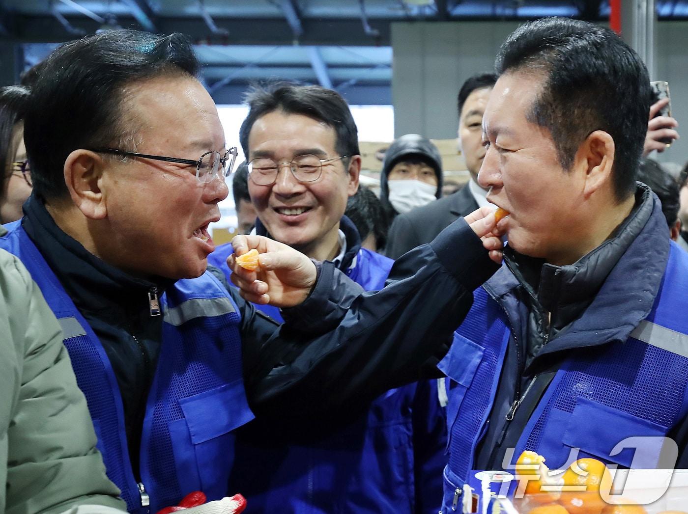 본문 이미지 - 8일 오전 대구 북구 대구농수산물도매시장에서 민생 현장 체험에 나선 정청래 더불어민주당 대표와 대구시장 선거에 출마한 김부겸 전 총리가 경매사의 안내를 받아 경매에서 낙찰된 수입산 감귤을 맛보고 있다. 정 대표는 1965년생, 김 전 총리는 1958년생으로 김 전 총리가 7살 많다. 2026.4.8 ⓒ 뉴스1 공정식 기자