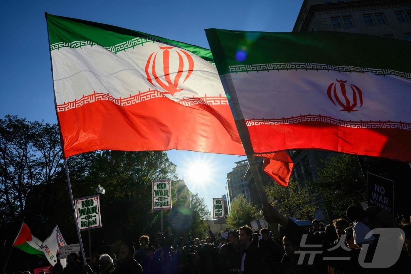 본문 이미지 - 7일(현지시간) 미국 백악관 인근에서 시위대가 이란에 대한 미국의 군사행동에 항의하며 이란 국기를 흔들고 있다. 2026.04.08. ⓒ AFP=뉴스1