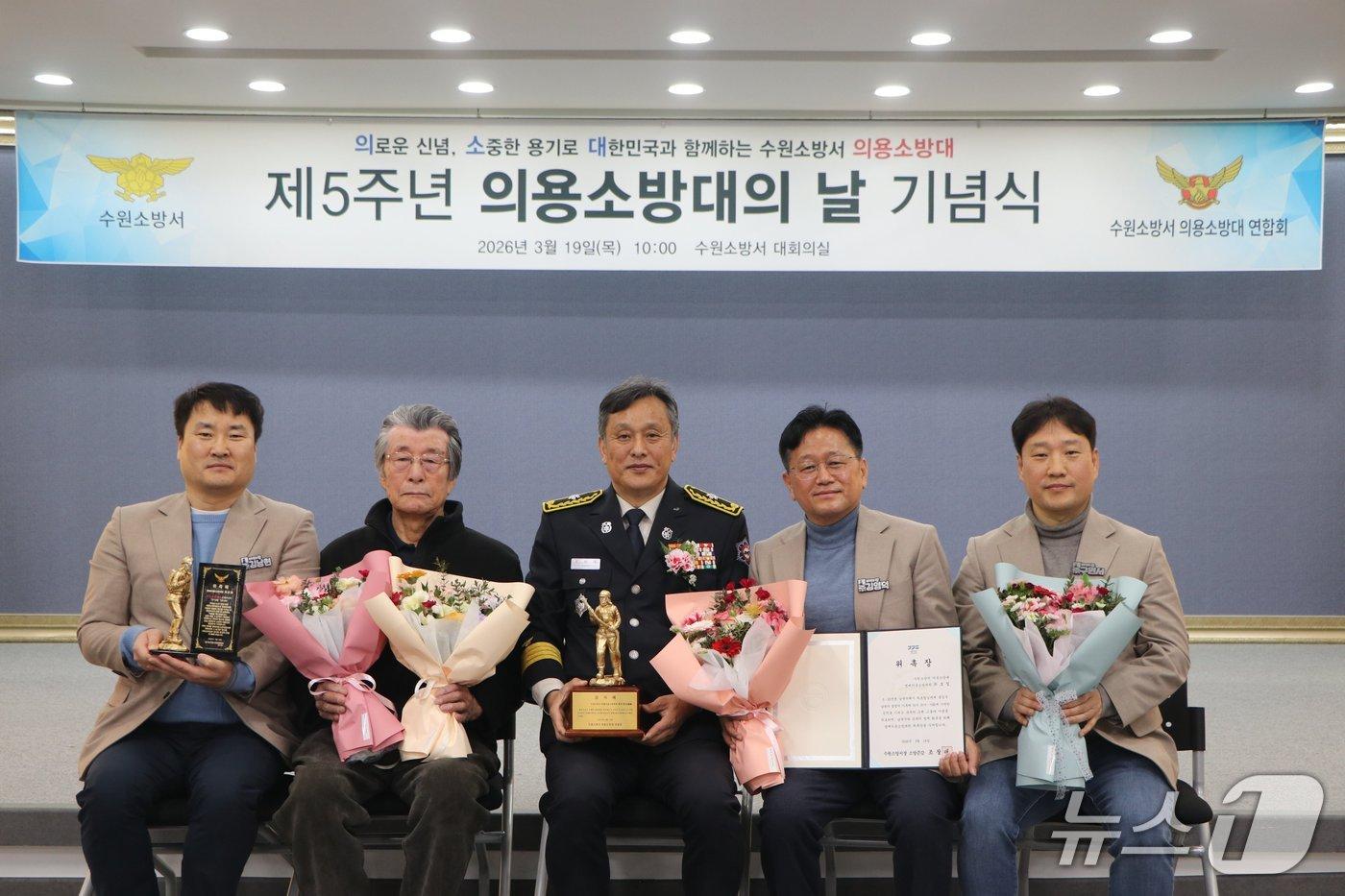 본문 이미지 - 최윤한 씨(왼쪽 두 번째)가 지난달 19일 수원소방서 대회의실에서 열린 '제5주년 의용소방대의 날 기념식'에서 아버지 고(故) 최호철 씨 명예의용소방대원 위촉장과 감사패를 받고 새빛민원실 베테랑팀장, 조창래 수원소방서장과 기념촬영을 하고 있다. (수원시 제공. 재판매 및 DB 금지) 2026.4.8/뉴스1 