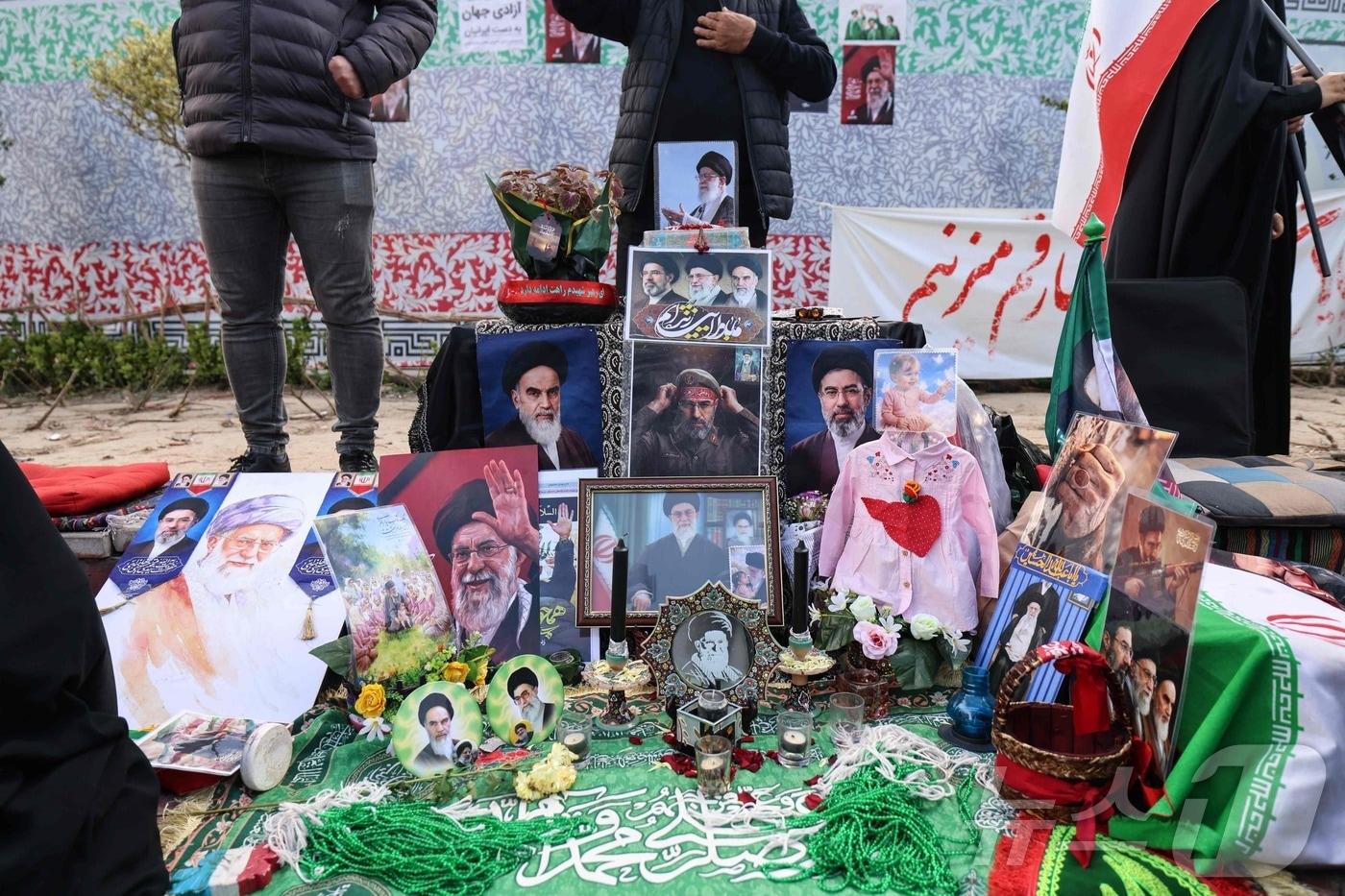 본문 이미지 - 8일(현지시간) 미국과 이란이 2주간의 휴전에 합의한 직후 테헤란 혁명광장에서 시민들이 임시 추모비 앞에 모여 서 있다. 2026.04.08.ⓒ AFP=뉴스1