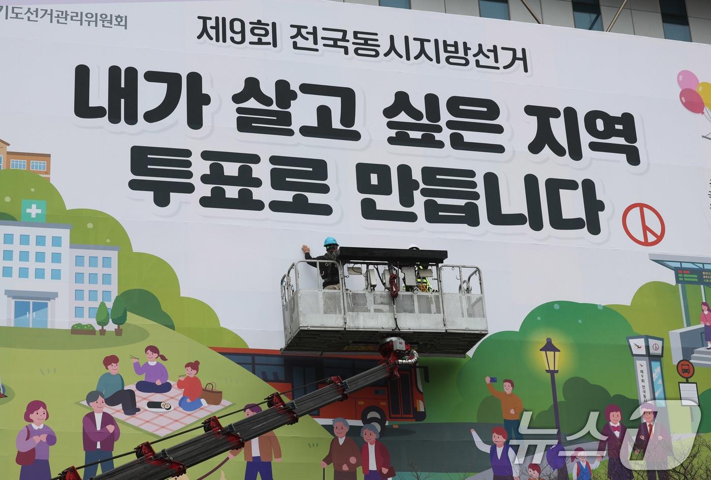 본문 이미지 - 제9회 전국동시지방선거를 앞둔 9일 경기도 수원시 영통구 경기도선거관리위원회 청사 외벽에 관계자들이 투표참여를 독려하는 대형 현수막을 설치하고 있다. 2026.4.9 ⓒ 뉴스1 박지혜 기자