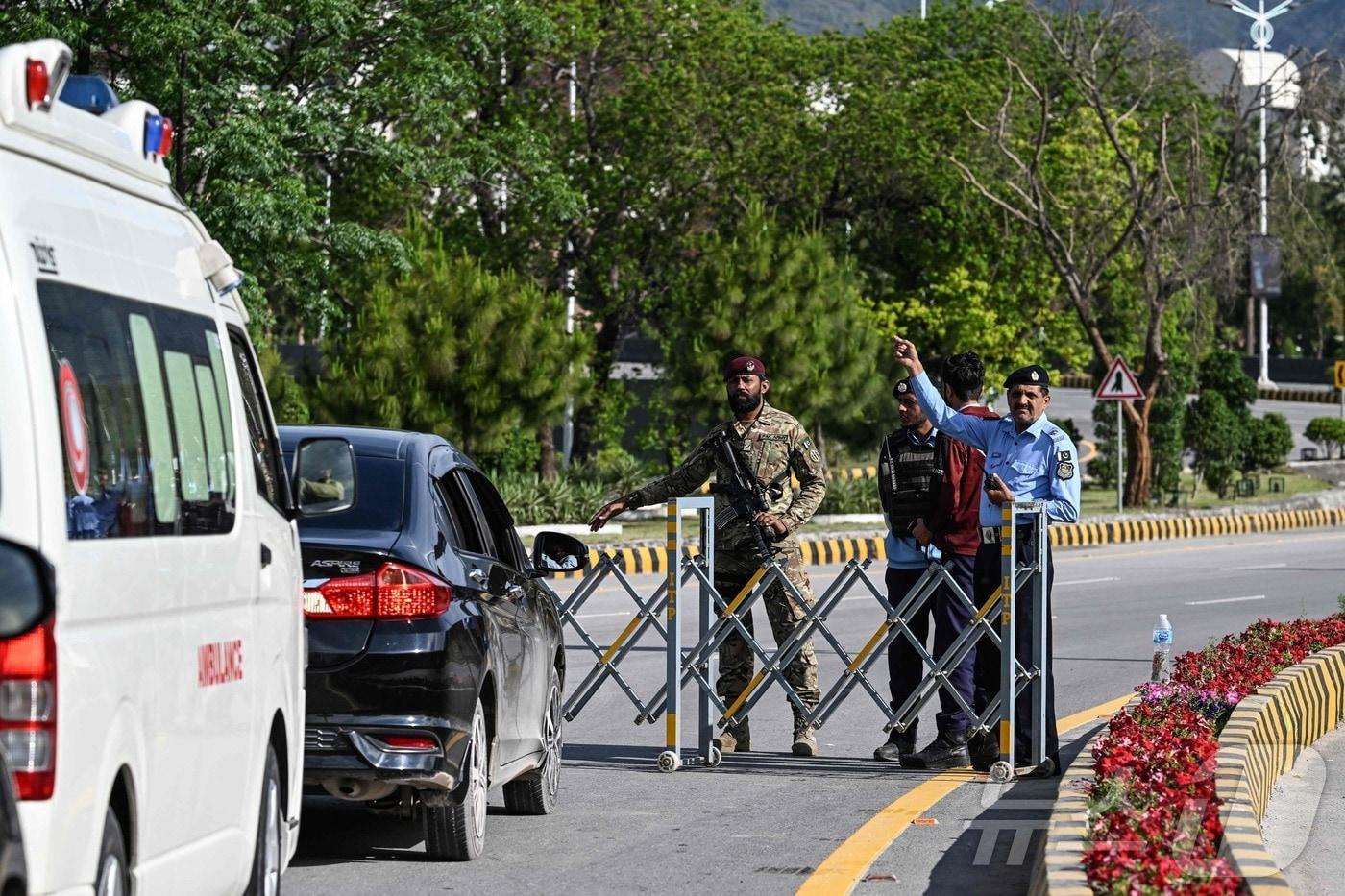 본문 이미지 - 9일(현지시간) 미국과 이란의 고위급 회담이 열릴 예정인 파키스탄 이슬라마바드 도심 '레드존'의 한 도로에서 경찰이 차량에게 돌아가라고 지시하고 있다. 2026.04.09 ⓒ AFP=뉴스1