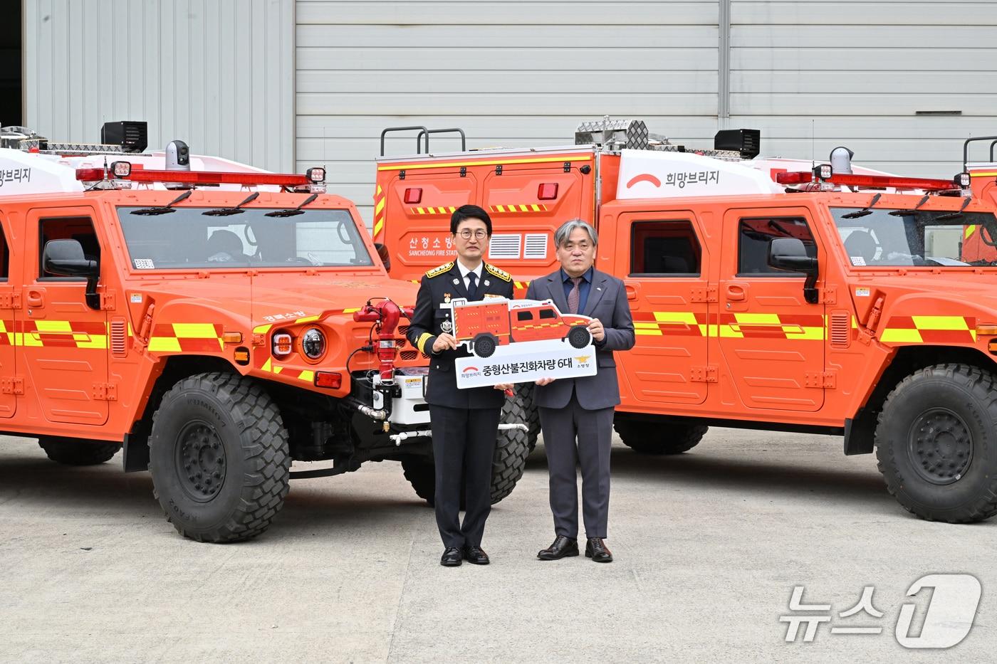 본문 이미지 - 9일 열린 중형 산불진화차량 전달식에서 김승룡 소방청장과 희망브리지 전국재해구호협회장이 산불진화차량 6대 기증 판넬을 들고 기념촬영을 하고 있다.(소방청 제공)