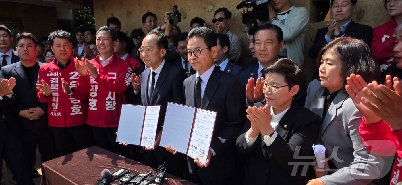 본문 이미지 - 1일 경북 구미 박정희 전 대통령 생가를 방문한 6·3 지방선거 국민의힘 이철우 경북지사 후보(오른쪽)와 추경호 대구시장 후보가 박 전 대통령 내외 영전에 헌화 후 작성한 공동 선언문을 펼쳐 보이고 있다. 2026.5.1 ⓒ 뉴스1 정우용 기자