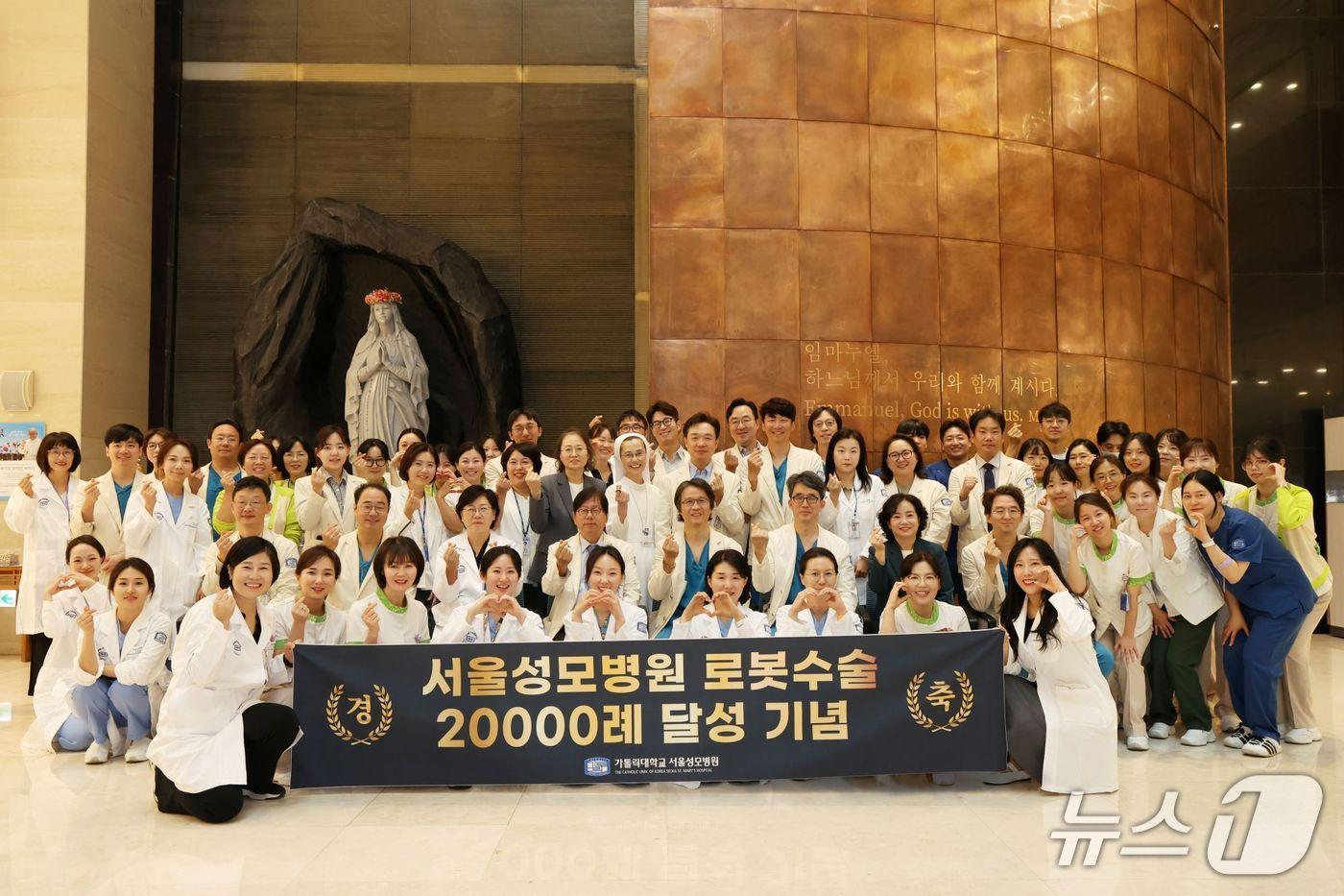 본문 이미지 - 11일 오전 서울성모병원 본관 1층 로비 성당 앞에서 이지열 병원장, 김혜경 간호부원장 등 주요 보직자와 전임 로봇수술센터장인 김미란 산부인과 교수, 송교영 위장관외과 교수를 비롯해 홍성후 센터장(비뇨의학과 교수) 등 여러 교직원들이 기념사진을 촬영했다.(서울성모병원 제공)