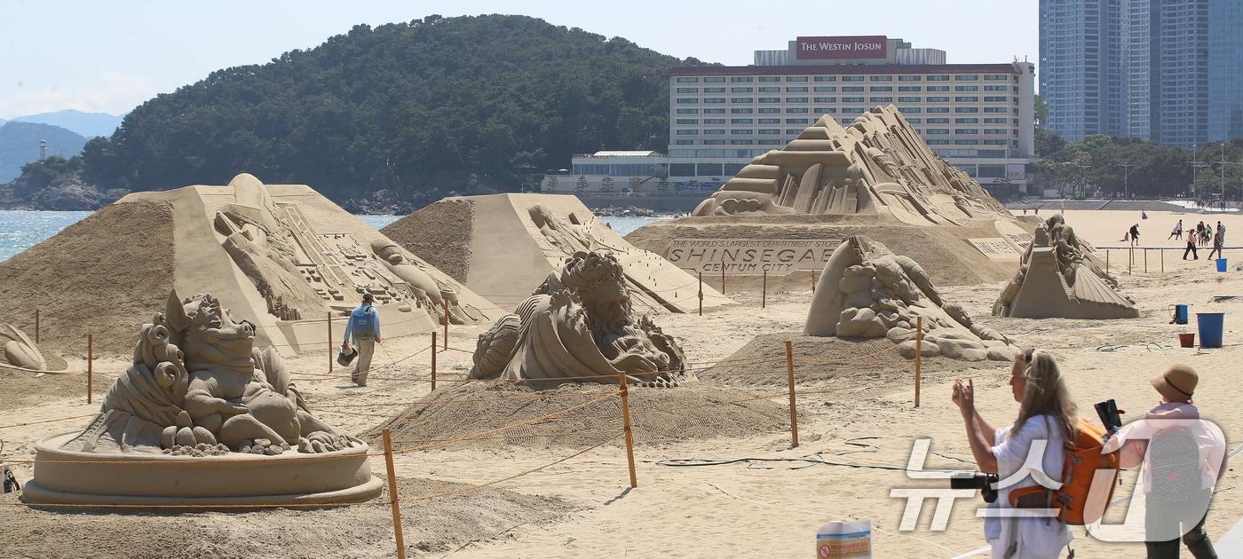 본문 이미지 - 11일 오후 부산 해운대해수욕장을 찾은 외국인 관광객들이 제작 중인 다양한 모래조각 작품을 구경하고 있다. 15~18일 이곳에서 열리는 '2026 해운대 모래축제'에서는 부산의 역사와 문화, 주요 랜드마크를 담은 모래 작품 17점이 전시될 예정이다. 2026.5.11 ⓒ 뉴스1 윤일지 기자