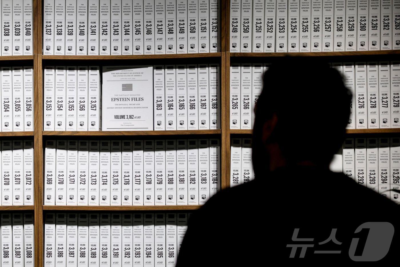 본문 이미지 - 11일(현지시간) 미국 뉴욕 맨해튼에서 한 방문객이 비영리단체 '일차 사실 연구소'(Institute of Primary Facts)가 주관한 전시회 '도널드 J. 트럼프·제프리 엡스타인 기념 열람실'에서 사건 연대표를 살펴 보고 있다. 이곳에는 엡스타인 수사 문서 전체 분량 350만쪽, 제본 3437권이 전시돼 있다. 전시회는 오는 21일까지 운영된다. 2026.05.11. ⓒ AFP=뉴스1