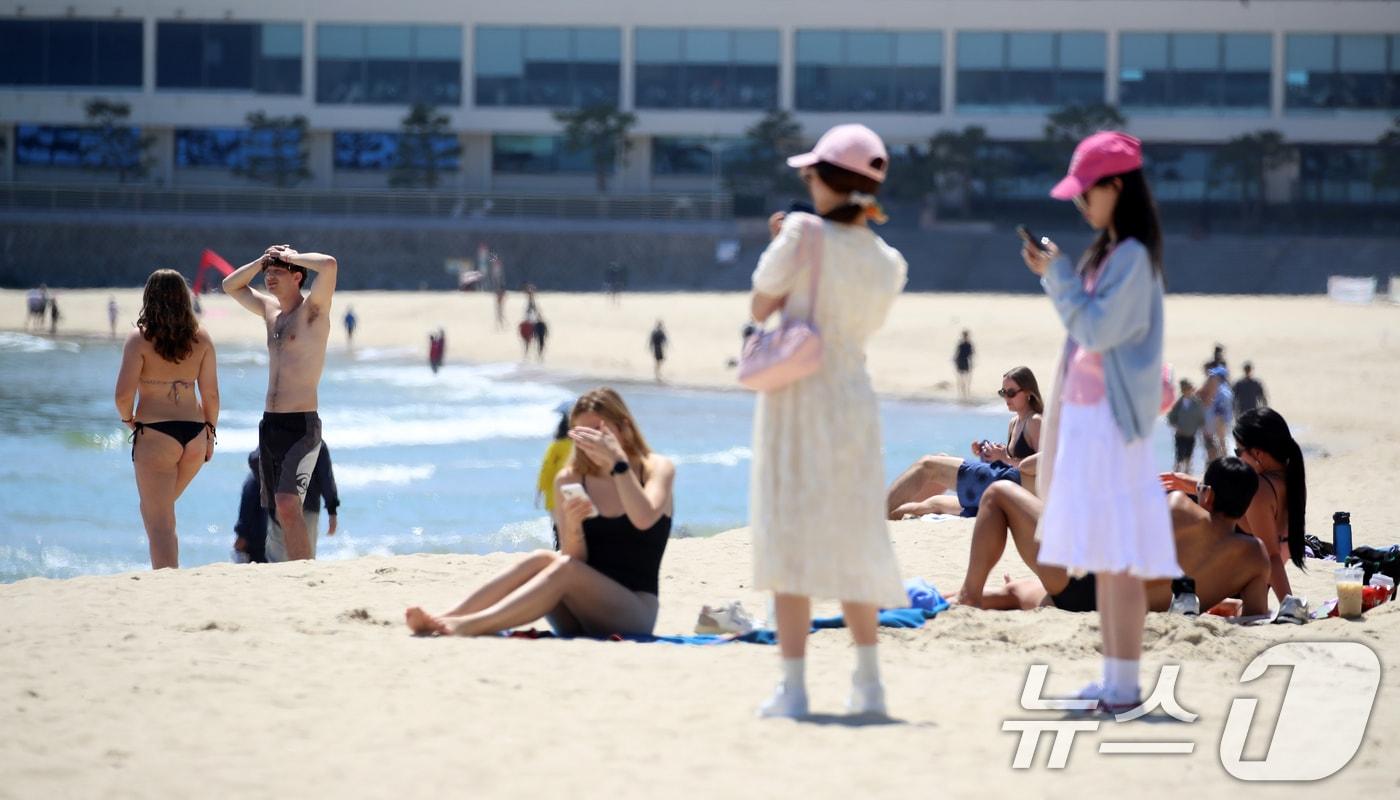 본문 이미지 - 전국적으로 초여름 날씨를 보인 13일 오후 부산 해운대해수욕장을 찾은 외국인들이 태닝을 즐기고 있다. 2026.5.13 ⓒ 뉴스1 윤일지 기자