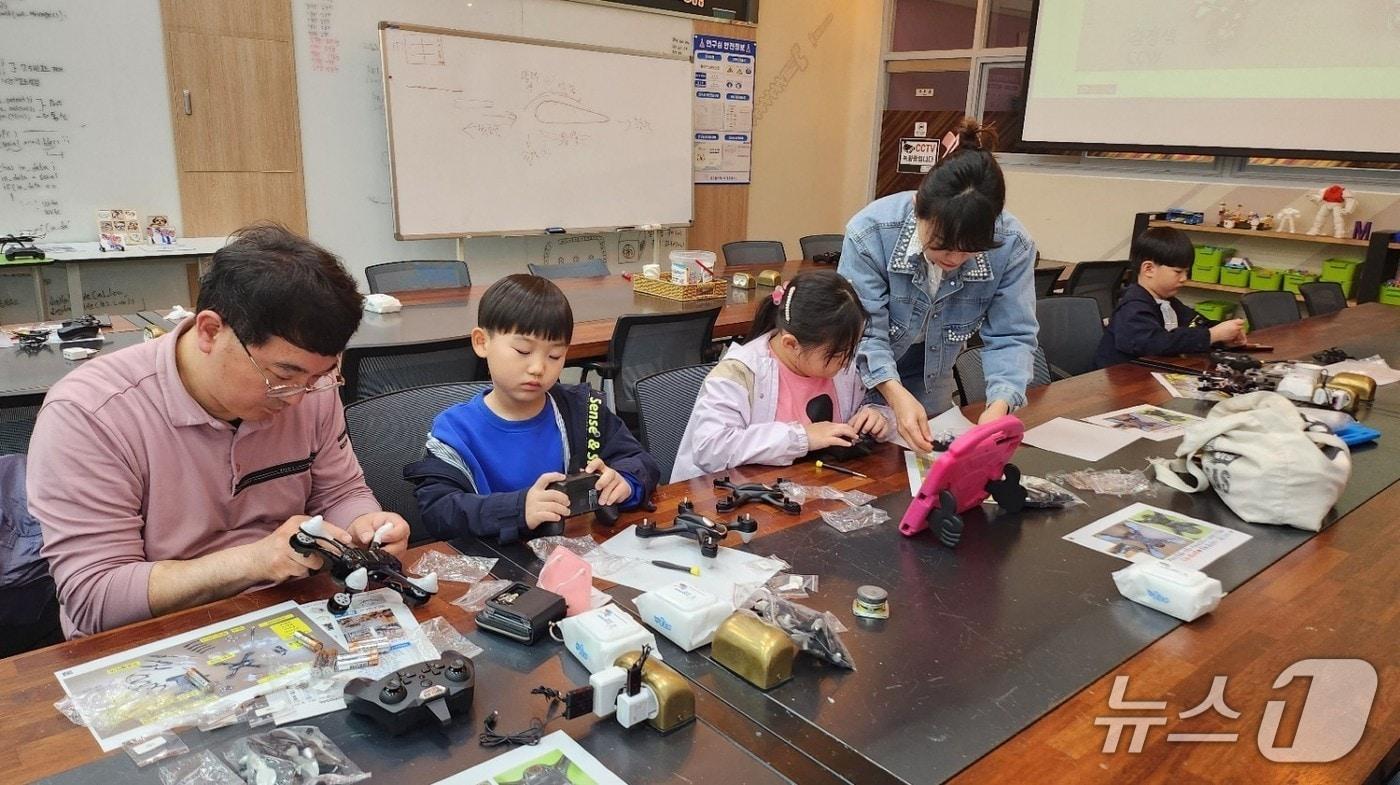 본문 이미지 - 한국폴리텍대학 광주캠퍼스 꿈드림공작소 ‘나만의 드론 만들기’ 프로그램에 참여한 가족이 드론을 조립하고 있다. (사진제공=고용노동부)