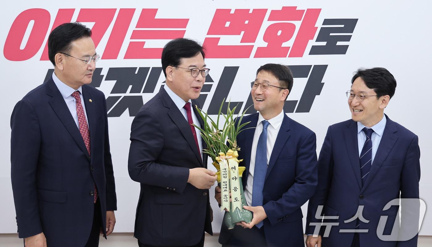 본문 이미지 - 연임된 한병도 더불어민주당 원내대표가 14일 서울 여의도 국회에서 송언석 국민의힘 원내대표를 예방하며 축하난을 선물받고 있다. 2026.5.14 ⓒ 뉴스1 신웅수 기자