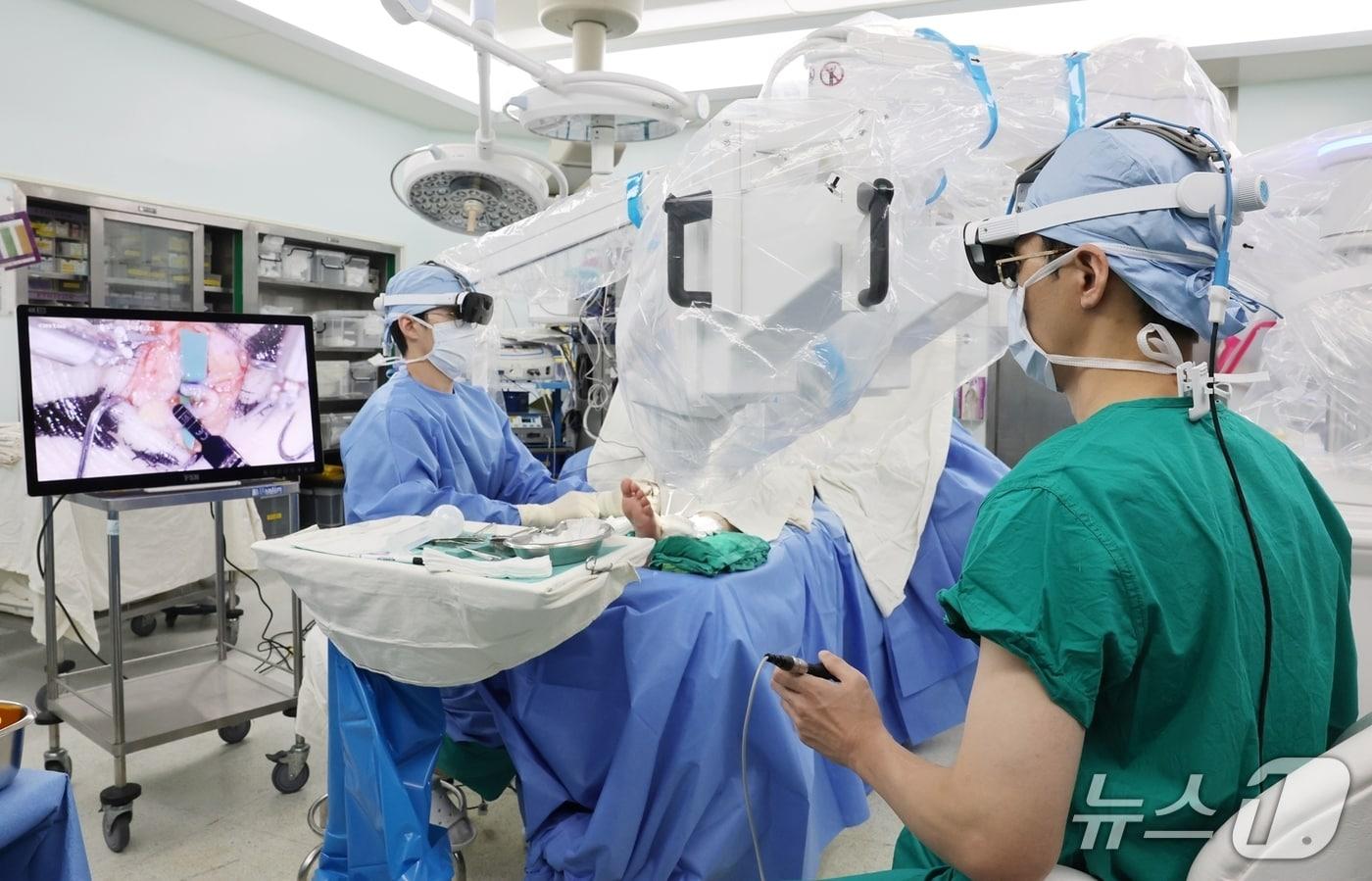 본문 이미지 - 권진근 서울아산병원 성형외과 교수(오른쪽)가 초미세수술 로봇을 이용해 하지 림프부종 환자에게 0.4mm 정도의 가느다란 림프관을 정맥에 연결하는 림프정맥간 문합술을 시행하고 있다.(서울아산병원 제공)