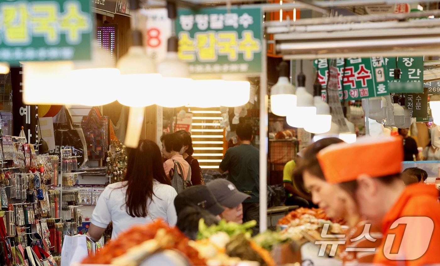 본문 이미지 - 18일 오전 서울 종로구 광장시장에서 외국인 관광객들이 먹거리를 구매하고 있다. 종로구는 오는 6월 1일부터 바가지요금 근절 등을 위해 노점 실명제를 시행할 예정이다. 2026.5.18 ⓒ 뉴스1 조연우 인턴기자
