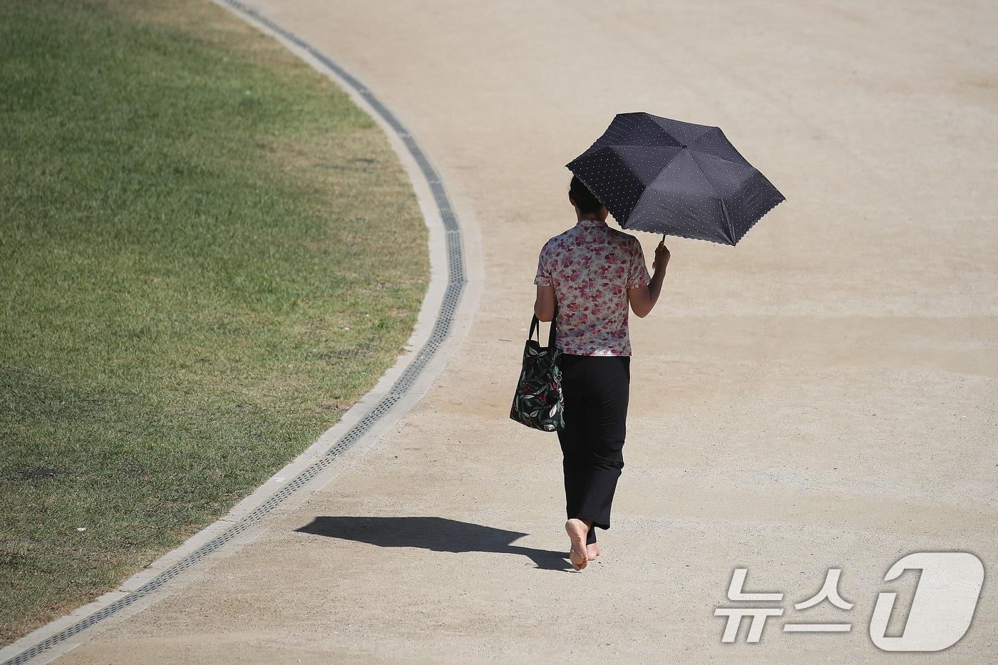 본문 이미지 - 대구의 낮 최고기온이 35도를 넘어 한여름 날씨를 보인 18일 대구 달서구 두류공원에서 한 시민이 양산으로 뙤약볕을 가린 채 맨발로 걷고 있다. 2026.5.18 ⓒ 뉴스1 공정식 기자