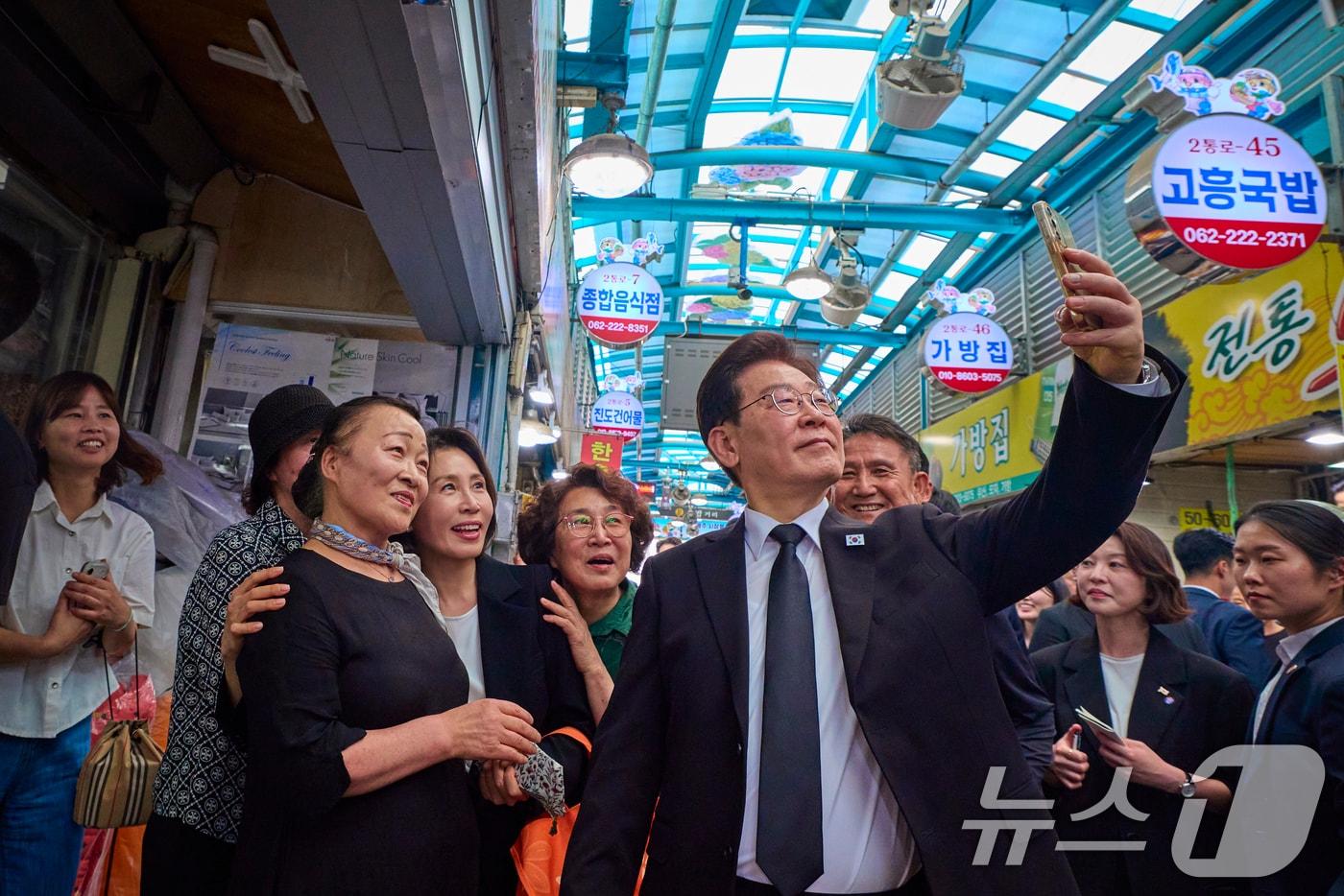 본문 이미지 - 이재명 대통령과 김혜경 여사가 18일 광주 동구 남광주시장을 찾아 시민들과 기념촬영을 하고 있다. (청와대 제공. 재판매 및 DB 금지) 2026.5.18 ⓒ 뉴스1 이재명 기자