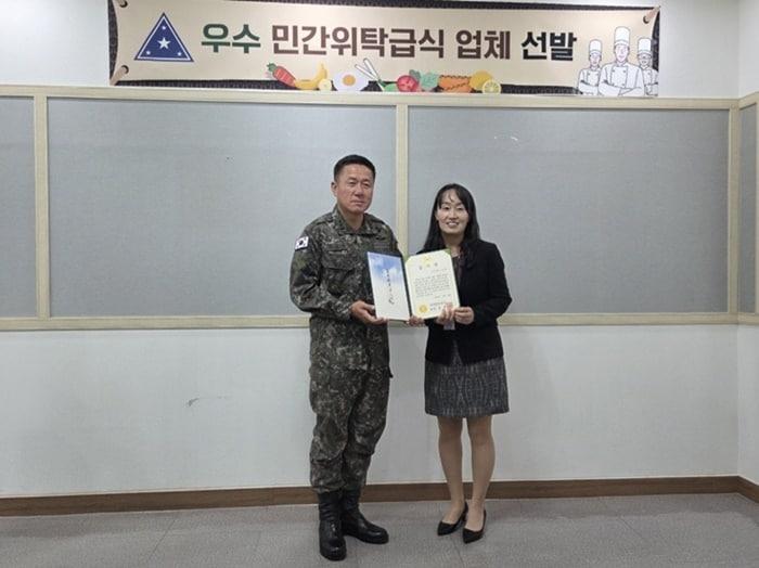 본문 이미지 - 성웰스토리가 운영 중인 육군3사학교가 육군 최우수 민간위탁급식 부대로 선정됐다. (왼쪽부터) 하헌철 육군본부 군수참모부 소장, 조성애 삼성웰스토리 지역장.(삼성웰스토리 제공)