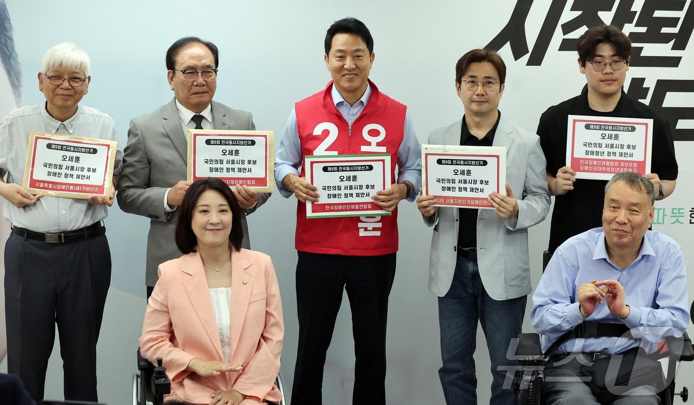 본문 이미지 - 오세훈 국민의힘 서울시장 후보가 19일 오전 서울시 종로구 선거 캠프에서 열린 서울시 장애인단체 관계자들과의 간담회를 마친 뒤 정책 제안서를 들고 기념 촬영을 하고 있다. 2026.5.19 ⓒ 뉴스1 김진환 기자