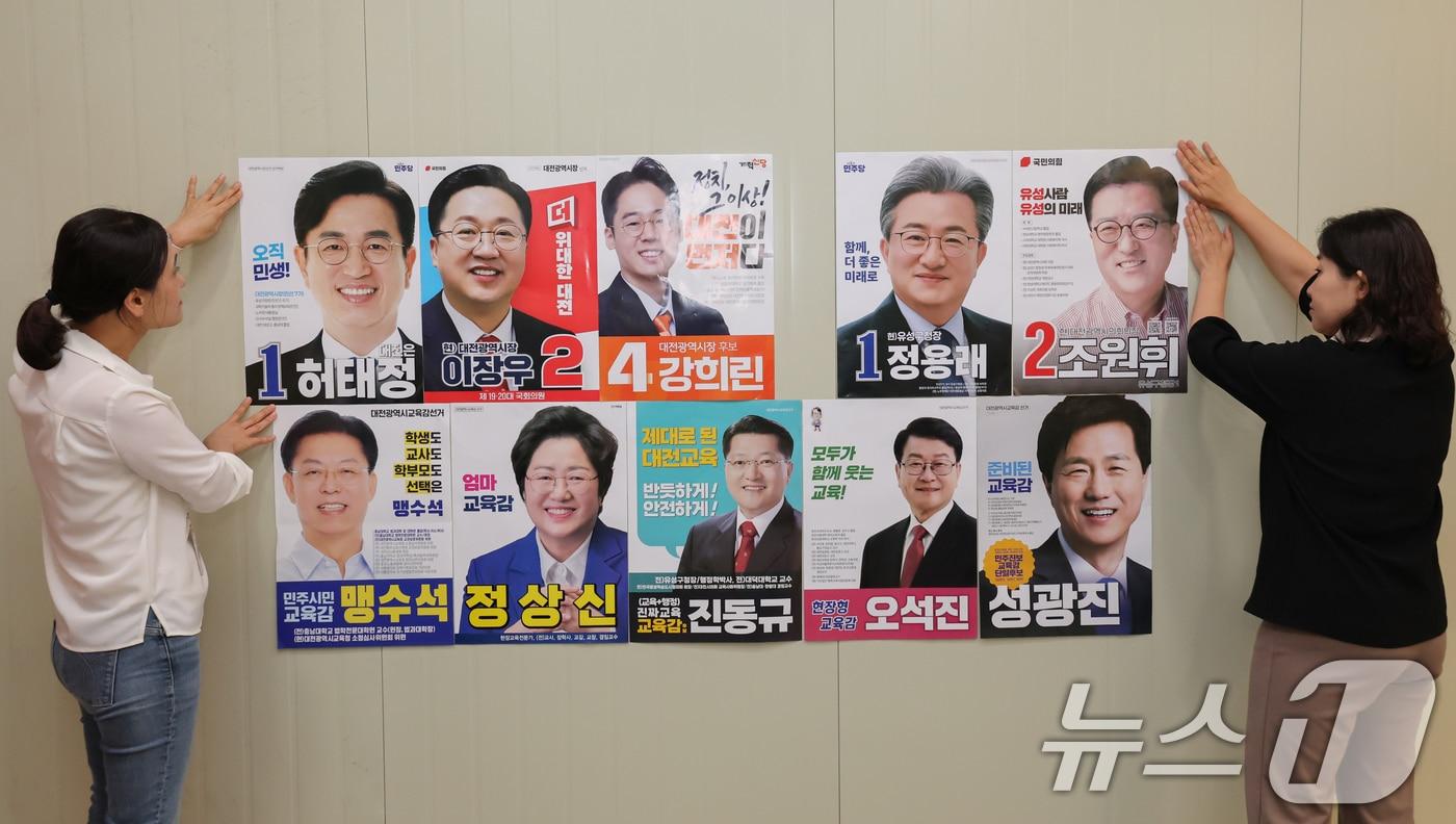 본문 이미지 - 제9회 전국동시지방선거 공식 선거운동을 하루 앞둔 20일 대전시선거관리위원회에서 선관위 직원들이 후보자 선거 벽보를 살피고 있다. 선거벽보는 대전 765곳, 충남 2344곳에 게시되며, 후보자 사진과 성명, 기호, 소속 정당명, 학력과 경력, 정견 및 정당 정책 등 유권자 판단에 필요한 정보가 담긴다. 후보자의 재산·병역·납세·전과 기록과 정책·공약 등이 담긴 책자형 선거공보도 오는 24일까지 각 가정으로 발송할 예정이다. 2026.5.20 ⓒ 뉴스1 김기태 기자