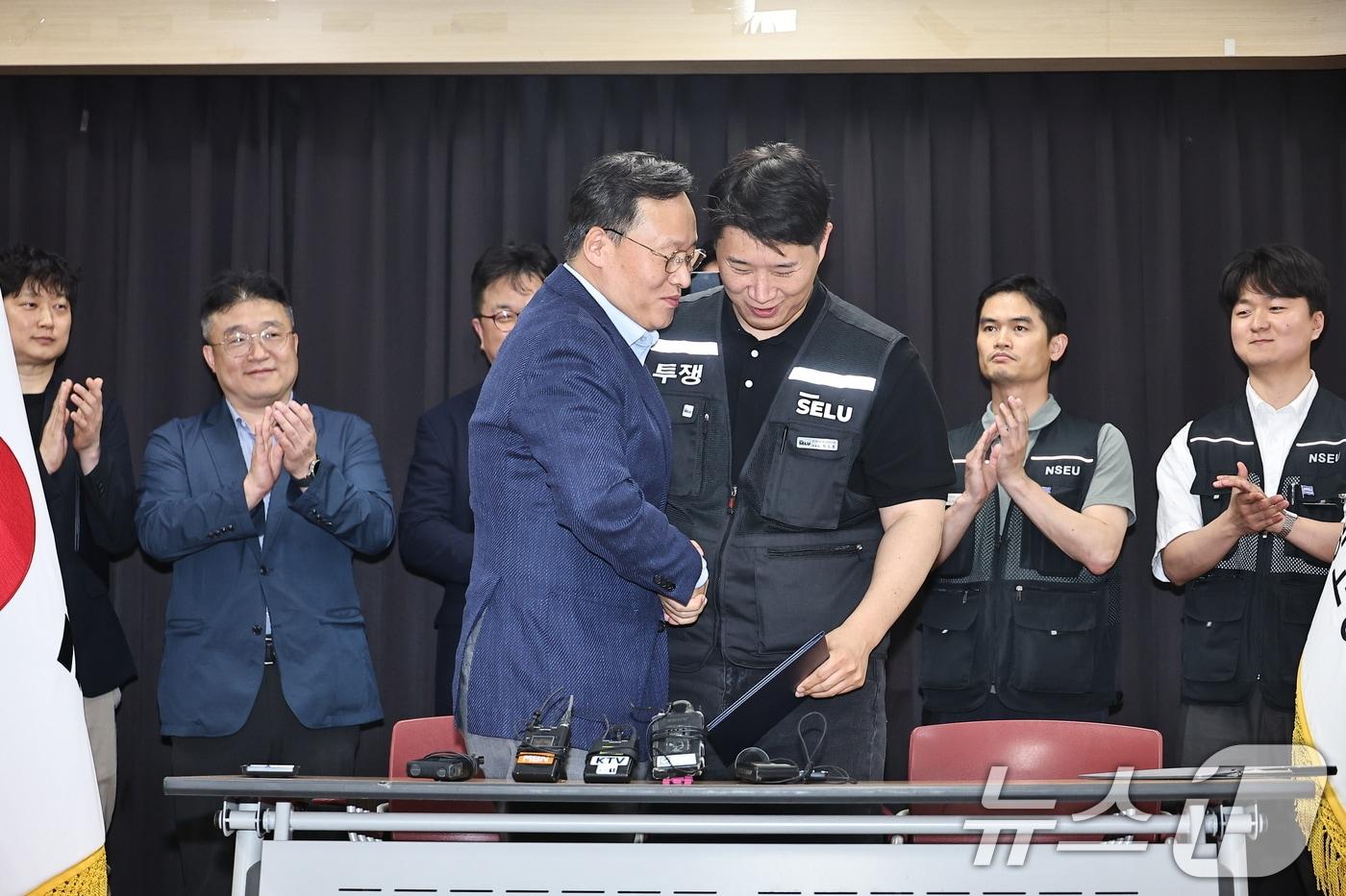 본문 이미지 - 20일 경기도 수원시 장안구 경기고용노동청에서 열린 삼성전자 임금협상을 마친 후 여명구 삼성전자 DS(디바이스솔루션·반도체 사업 담당) 피플팀장과 최승호 삼성그룹 초기업노동조합 삼성전자지부 위원장이 잠정 합의한에 서명한 후 손을 맞잡고 있다. (공동취재) 2026.5.20 ⓒ 뉴스1 김영운 기자