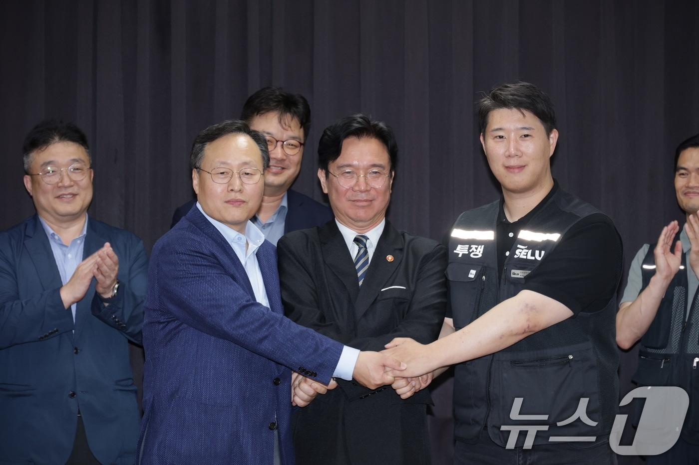 본문 이미지 - 20일 경기도 수원시 장안구 경기고용노동청에서 열린 삼성전자 임금협상을 마친 후 여명구 삼성전자 DS(디바이스솔루션·반도체 사업 담당) 피플팀장과 김영훈 고용노동부 장관, 최승호 삼성그룹 초기업노동조합 삼성전자지부 위원장이 잠정 합의한에 서명한 후 손을 맞잡고 있다. (공동취재) 2026.5.20 ⓒ 뉴스1 김영운 기자
