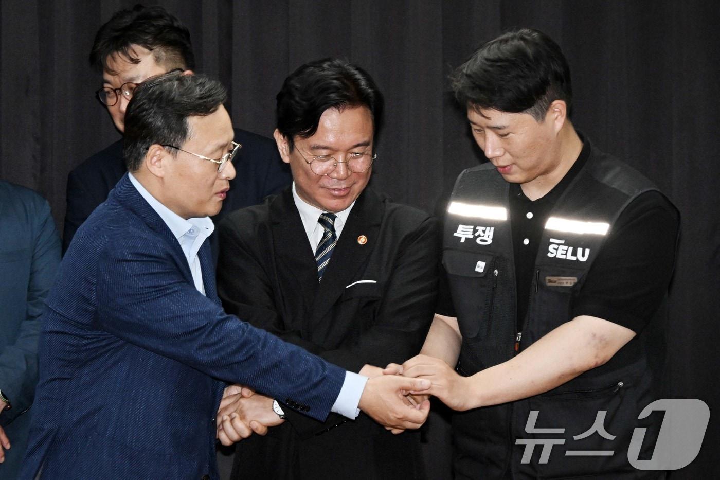 본문 이미지 - 20일 경기도 수원시 장안구 경기고용노동청에서 열린 삼성전자 임금협상을 마친 후 여명구 삼성전자 DS(디바이스솔루션·반도체 사업 담당) 피플팀장과 김영훈 고용노동부 장관, 최승호 삼성그룹 초기업노동조합 삼성전자지부 위원장이 잠정 합의한에 서명한 후 손을 맞잡고 있다. (공동취재) 2026.5.20 ⓒ 뉴스1 김영운 기자