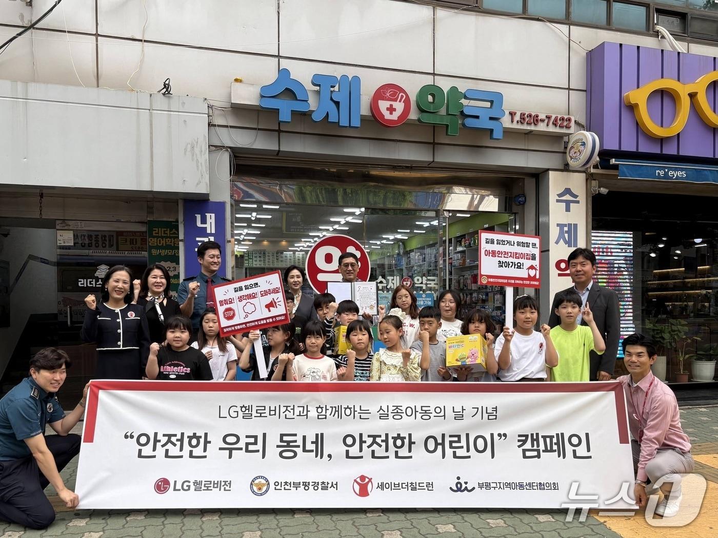 본문 이미지 - 사진은 인천 부평구 소재의 한 아동안전지킴이집(수제약국) 앞에서 관계자들과 지역아동센터 아이들이 아동 안전망 구축을 다짐하며 단체 기념촬영을 하고 있는 모습. (LG헬로비전 제공)