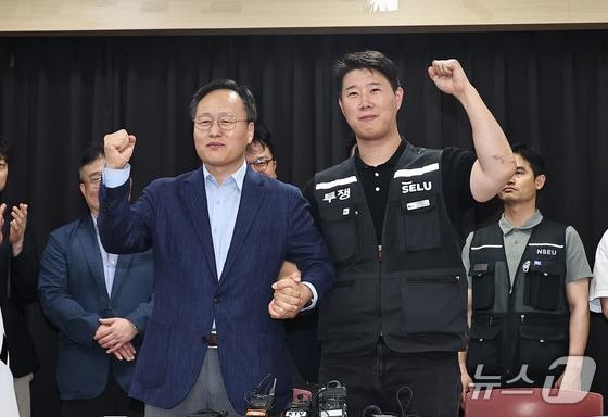 본문 이미지 - 20일 경기 수원시 장안구 경기고용노동청에서 열린 삼성전자 임금협상을 마친 후 여명구 삼성전자 반도체(DS) 피플팀장(왼쪽)과 최승호 삼성그룹 초기업노동조합 삼성전자지부 위원장이 잠정 합의안에 서명한 후 파이팅을 외치고 있다. (공동취재) 2026.5.20/뉴스1