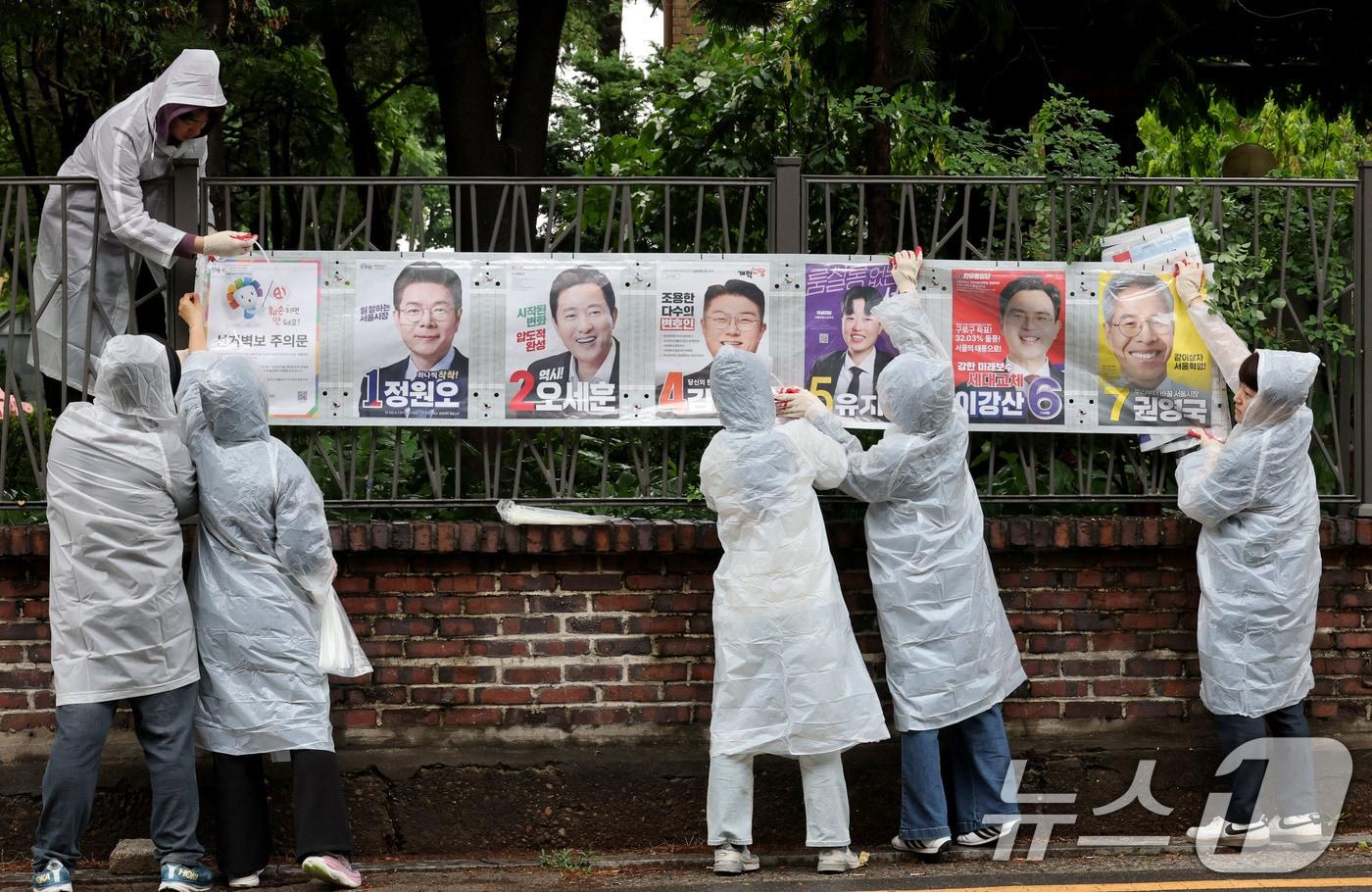 본문 이미지 - 제9회 전국동시지방선거 공식 선거운동이 시작된 21일 오전 서울 종로구 예술가의 집 담장에 서울시선관위 직원들이 선거벽보를 첩부하고 있다. 2026.5.21 ⓒ 뉴스1 이광호 기자