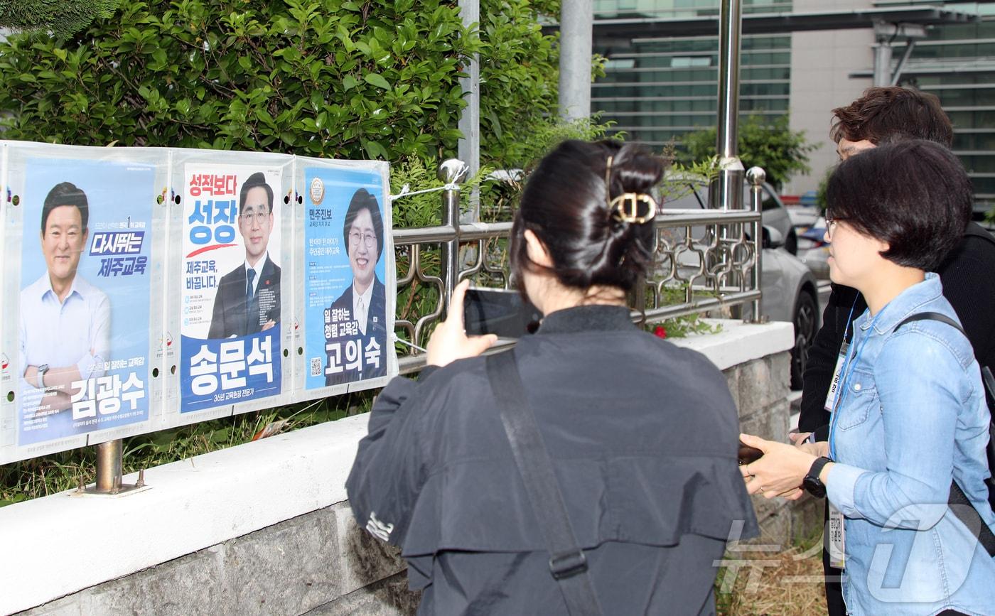 본문 이미지 - 시민들이 22일 오전 제주시 이도2동 통계교육원 제주수련원 정문 울타리에 붙여진 제9회 전국동시지방선거 제주도지사·제주도교육감 선거 후보자 선거벽보를 살펴보고 있다. 2026.5.22 ⓒ 뉴스1 오미란 기자