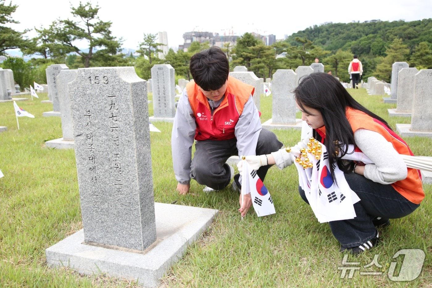 본문 이미지 - SKC 구성원들이 21일 오후 국립서울현충원 묘비 앞에 태극기를 꽂으며 묘역 정화 활동을 진행하고 있다(SKC 제공). 2026.5.21.