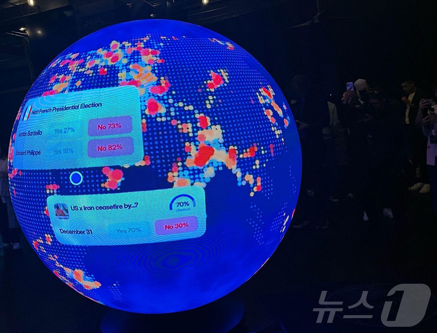 본문 이미지 - 2026년 3월 20일 미국 워싱턴DC에서 열린 예측시장 플랫폼 폴리마켓의 ‘더 시추에이션 룸(The Situation Room)’ 개장 행사에서 대형 LED 구형 스크린에 관련 정보가 표시되고 있다.ⓒ AFP=뉴스1