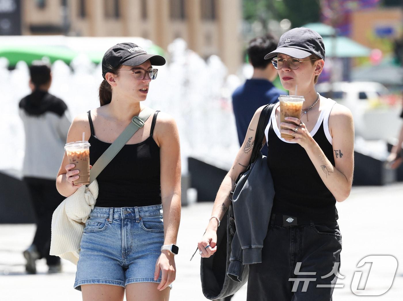 본문 이미지 - 낮 최고 기온이 27도까지 오르는 등 초여름 날씨를 보인 22일 오후 서울 종로구 광화문광장을 찾은 외국인 관광객들이 시원한 음료를 들고 발걸음을 옮기고 있다. 2026.5.22 ⓒ 뉴스1 임지훈 인턴기자