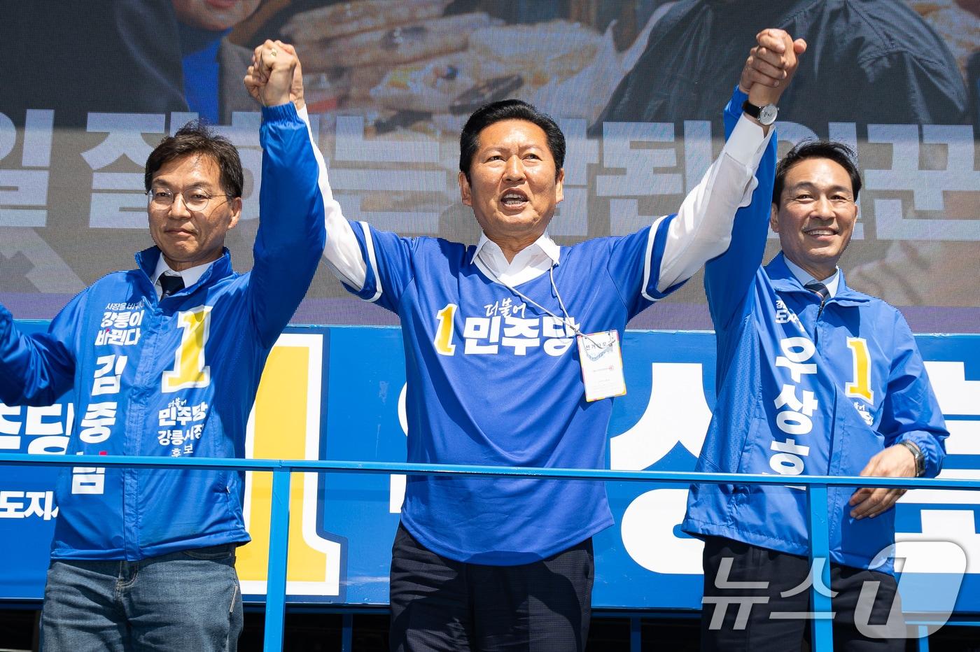 본문 이미지 - 정청래 더불어민주당 대표와 우상호 강원특별자치도지사 후보, 김중남 강릉시장 후보가 22일 강원 강릉시 주문진 시장 앞에서 손을 맞잡고 시민들을 향해 인사하고 있다. 2026.5.22 ⓒ 뉴스1 유승관 기자