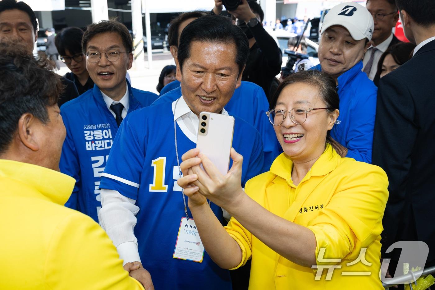 본문 이미지 - 우상호 강원특별자치도지사 후보와 김중남 강릉시장 후보 지원유세에 나선 정청래 더불어민주당 대표가 22일 강원 강릉시 주문진 시장에서 상인과 기념 촬영을 하고 있다. 2026.5.22 ⓒ 뉴스1 유승관 기자