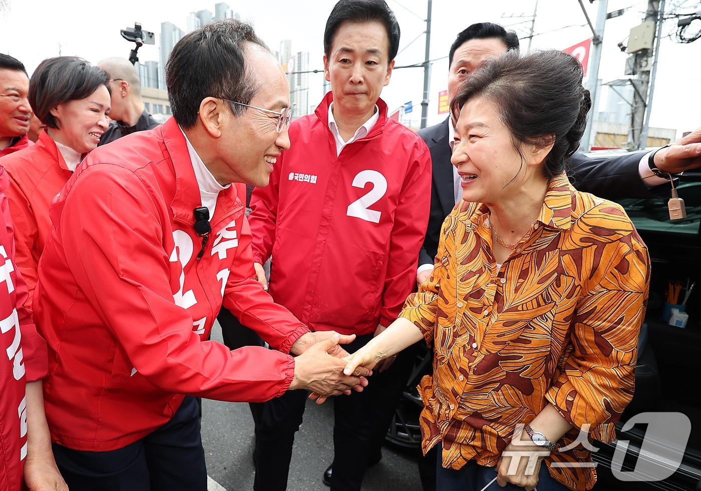 본문 이미지 - 박근혜 전 대통령이 23일 오후 대구 북구 칠성시장을 찾아 추경호 국민의힘 대구시장 후보와 만나 인사 나누고 있다. 2026.5.23 ⓒ 뉴스1 공정식 기자