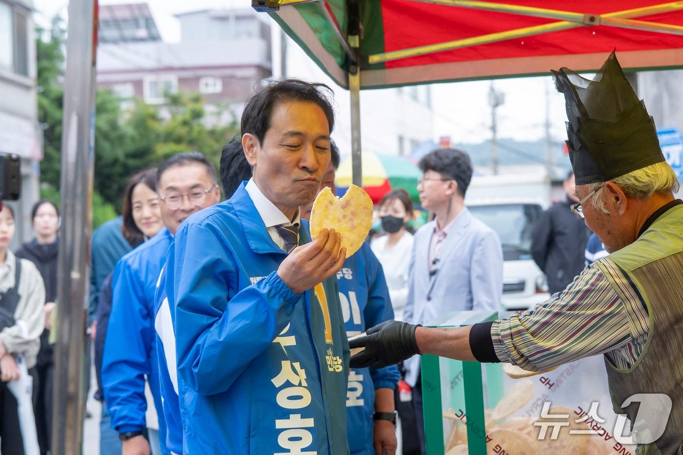 본문 이미지 - 우상호 더불어민주당 강원도지사 후보가 6·3 지방선거 공식 선거운동 첫 주말인 23일 동해시 북평오일장을 찾아 시장 상인에게 산 과자를 먹고 있다.(우 후보 캠프 측 제공, 재판매 및 DB 금지) 2026.5.23/뉴스1
