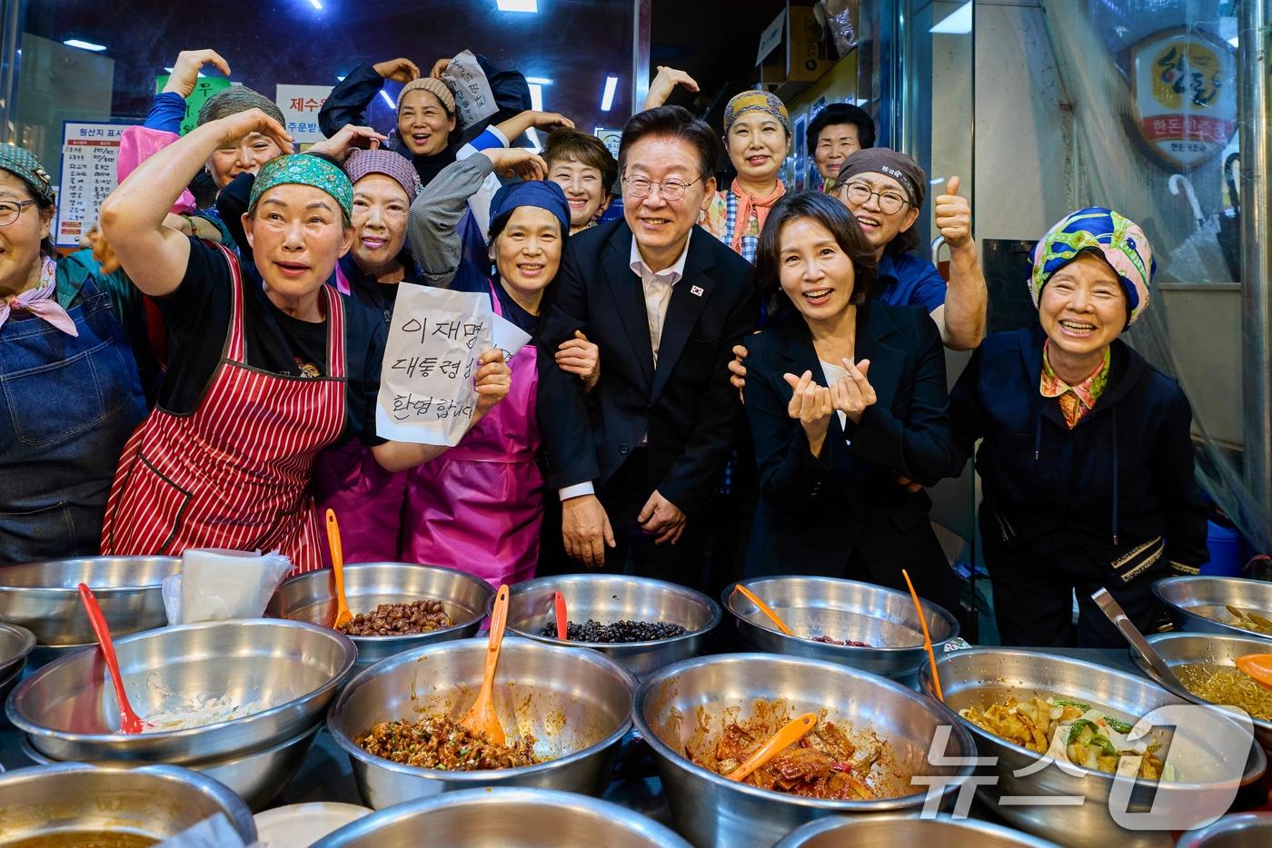 본문 이미지 - 이재명 대통령과 김혜경 여사가 23일 김해 외동전통시장을 찾아 상인들과 기념촬영을 하고 있다. (청와대 제공. 재판매 및 DB 금지) 2026.5.23 ⓒ 뉴스1 이재명 기자