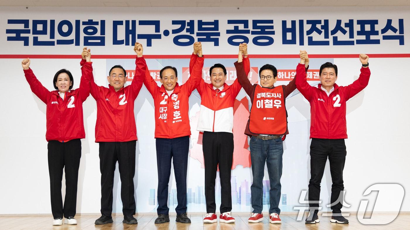 본문 이미지 - 장동혁 국민의힘 대표와 추경호 대구시장 후보, 이철우 경상북도지사 후보가 25일 대구 수성구 국민의힘 대구시당에서 열린 대구·경북 공동 비전선포식에서 손을 맞잡아 들고 있다. 왼쪽부터 이인선 대구시당위원장, 주호영 대구시당 총괄선대위원장, 추경호 대구시장 후보, 장 대표, 이철우 경북지사 후보, 구자근 경북도당위원장. 2026.5.25 ⓒ 뉴스1 유승관 기자