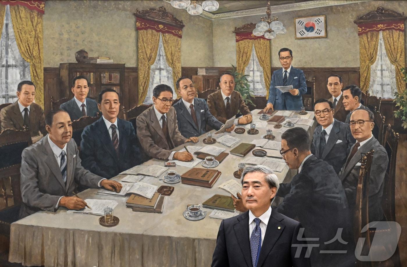 본문 이미지 - 신현송 한국은행 총재가 지난 5월 취임 후 첫 금융통화위원회 본회의에 참석하고 있다. 배경은 현재 한국은행 금융통화위원회 회의실에 걸려 있는 '제1차 금융통화위원회 회의 장면' 유화. 1950년 6월 5일 열린 첫 금통위 회의를 화가 김태가 1987년 그린 작품이다. ⓒ 뉴스1