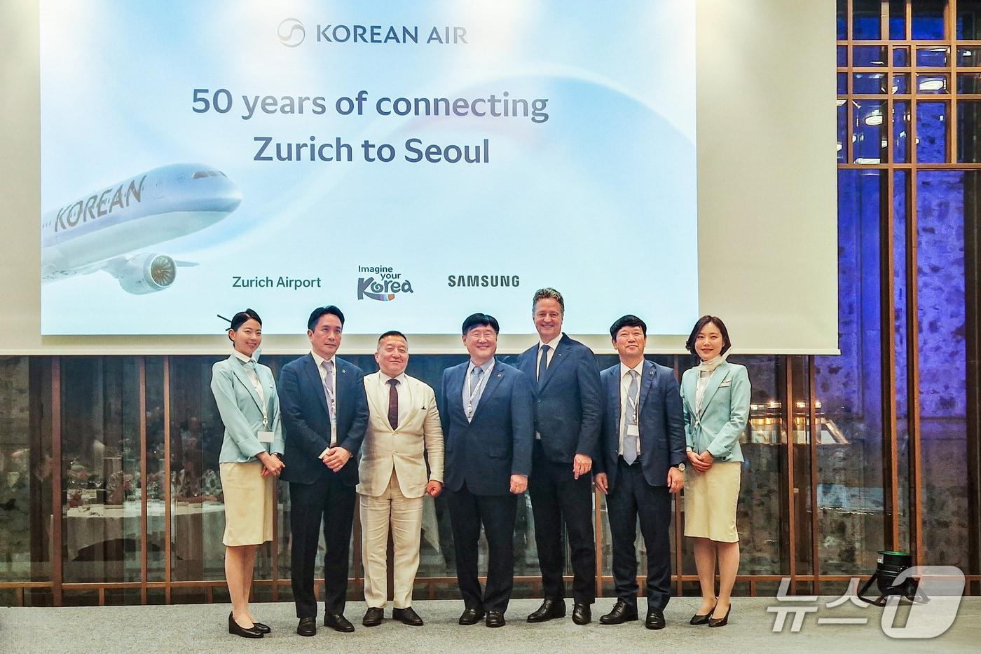 본문 이미지 - 대한항공이 스위스 취리히 노선 취항 50주년을 기념해 27일(현지시간) 취리히 비더 호텔에서 개최한 행사에서 최정호 대한항공 영업 총괄 부사장(가운데), 이석우 대한항공 여객영업부 담당 상무(오른쪽 두번째), 신우식 주스위스 대한민국 대사 대리(왼쪽 세번째), 스테판 그로스 취리히 공항 최고책임자(오른쪽 세번째) 등이 기념 사진을 촬영한 모습(대한항공 제공). 2026.5.27.