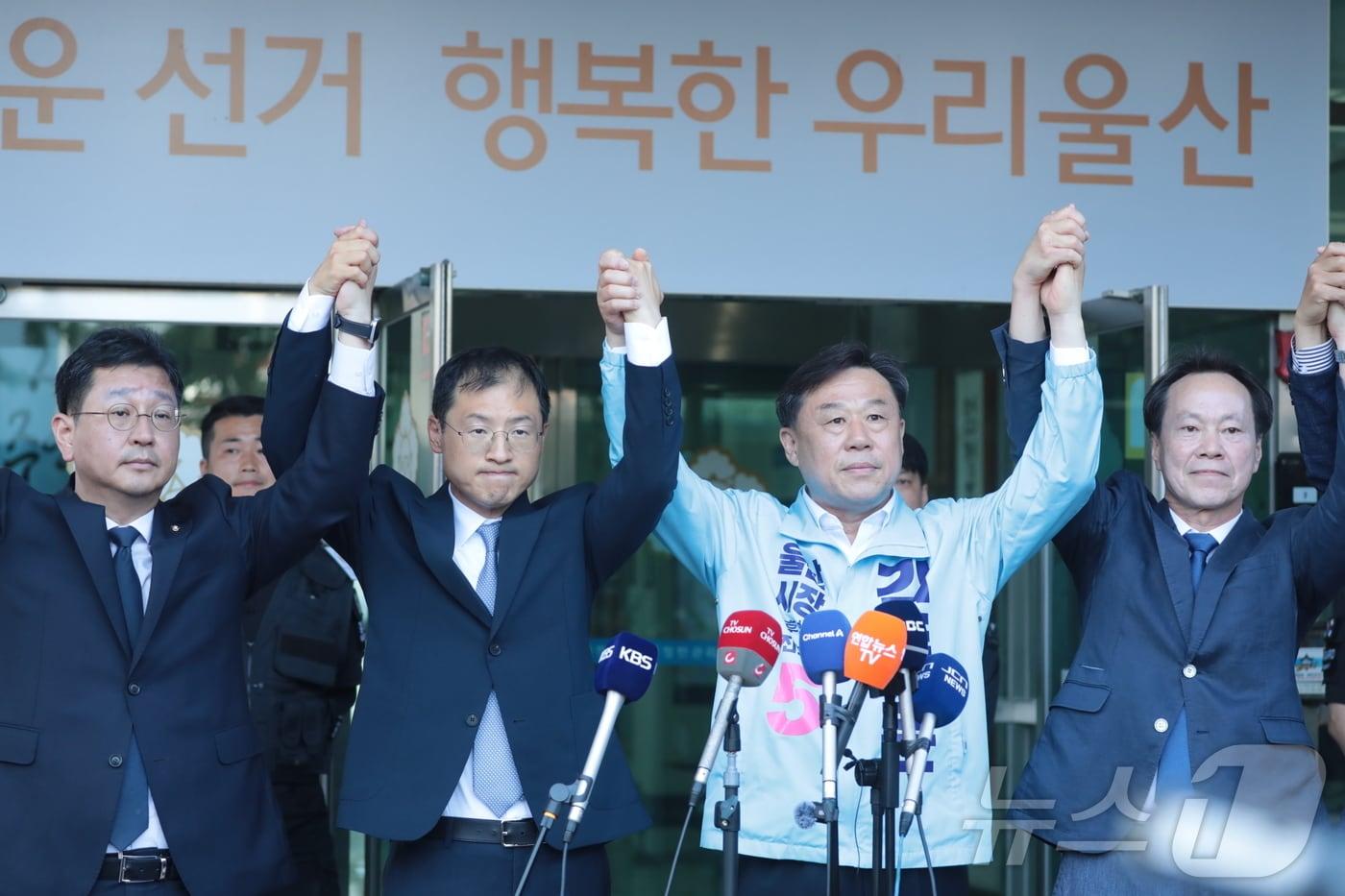 본문 이미지 - 김상욱 더불어민주당(왼쪽에서 두 번째), 김종훈 진보당 울산시장 후보가 28일 울산 중구 울산시선거관리위원회 앞에서 기자회견을 열고 김상욱 후보로의 단일화를 선언하며 손을 잡아 들어보이고 있다. 2026.5.28 ⓒ 뉴스1 박정현 기자