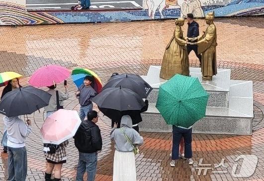 본문 이미지 - 조선 6대 임금 단종을 다룬 영화 '왕과 사는 남자' (왕사남)가 1670만여 누적 관객을 동원하면서 흥행한 가운데, 5월 첫 일요일인 지난 3일 단종 유배지였던 강원 영월군 청령포 주변에 있는 '천상재회 동상에 여행객들이 몰려들고 있다. 동상은 조선 6대 임금 단종과 그의 왕비 정순왕후의 사랑이야기를 소개하고 있는데, 여행객들은 이날 비 날씨에도 우산을 들고 이곳을 찾았다. ⓒ 뉴스1 신관호 기자