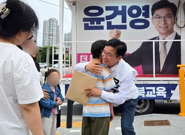 본문 이미지 - 윤건영 충북교육감 후보가 부모와 함께 유세 현장을 찾아 정책 제안서를 전달한 학생을 안아주고 있다.(선거캠프 제공. 재판매 및 DB금지)/뉴스1