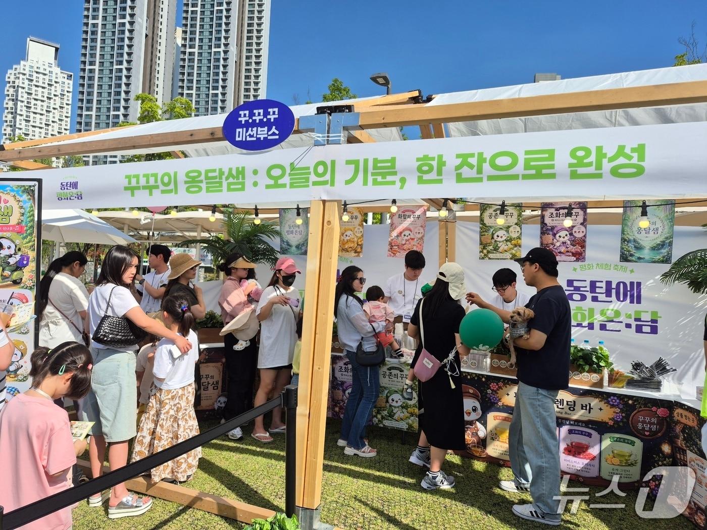 본문 이미지 - 통일부 청년인턴들이 기획한 참여형 미션 부스 ‘꾸꾸의 옹달샘’에서 가족 단위 지역주민들이 미션을 수행하기 위해 차례를 기다리며 행사를 즐기고 있다. (화성시 제공)