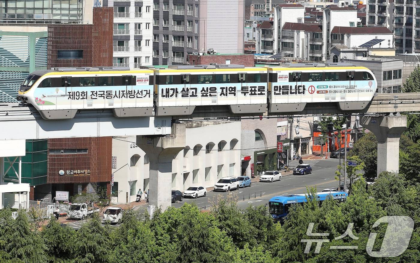 본문 이미지 - 제9회 전국동시지방선거가 29일 앞으로 다가온 5일 대구도시철도 3호선 '선거 열차'가 녹음 짙어가는 도심을 지나고 있다. 대구시선관위는 지방선거를 앞두고 유권자의 관심과 투표 참여를 독려하기 위해 열차 내·외부를 선거 관련 정보로 꾸민 '선거 열차'를 오는 6월 3일까지 운행한다. 2026.5.5 ⓒ 뉴스1 공정식 기자