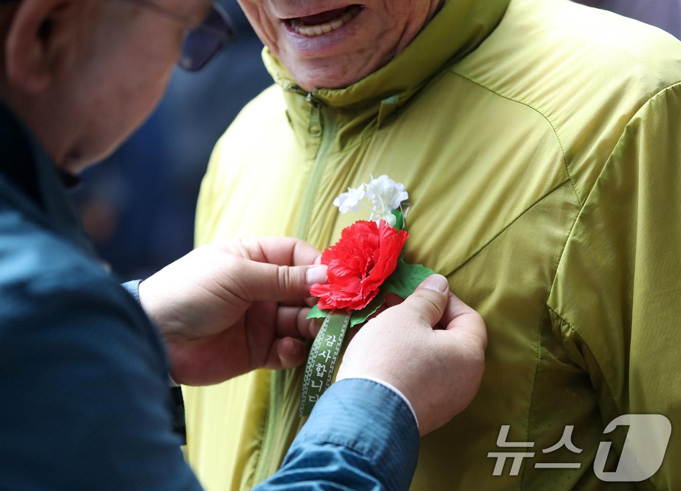 본문 이미지 - 어버이날을 하루 앞둔 7일 대구 달서구 두류공원 '사랑해밥차' 무료급식소에서 봉사자들이 어르신에게 카네이션을 달아주고 있다. 2026.5.7 ⓒ 뉴스1 공정식 기자