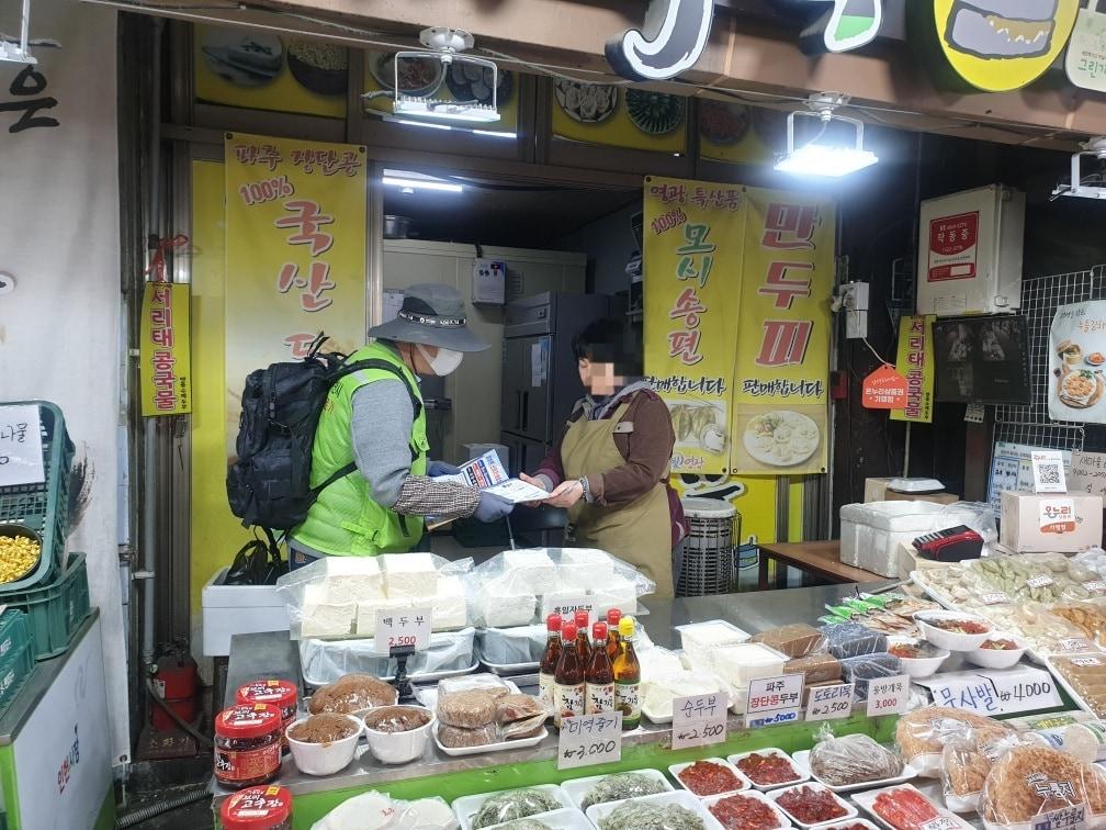 본문 이미지 - 지난 4월 관악구 무단투기보안관이 인헌시장 상인에게 홍보물을 전달하고 있다.(관악구 제공)