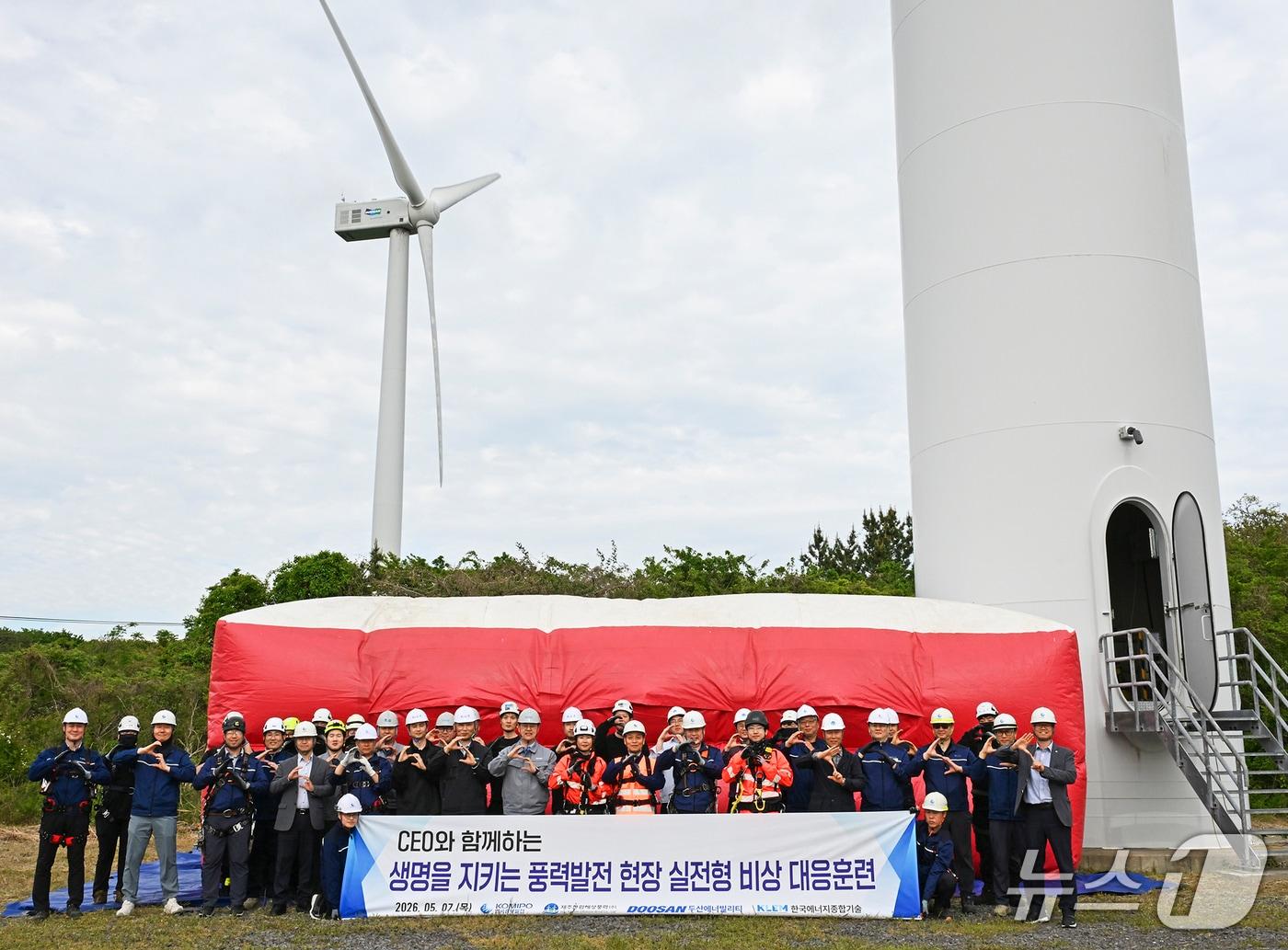 본문 이미지 - 한국중부발전 제주 풍력발전단지 화재 대응 합동훈련 후 관계자들이 안전을 형상화한 손모양(Safety)으로 구호를 외치며 기념사진을 촬영하고 있다. (첫째줄 오른쪽에서 여덟 번째 이영조 한국중부발전 사장. 사진제공=중부발전)