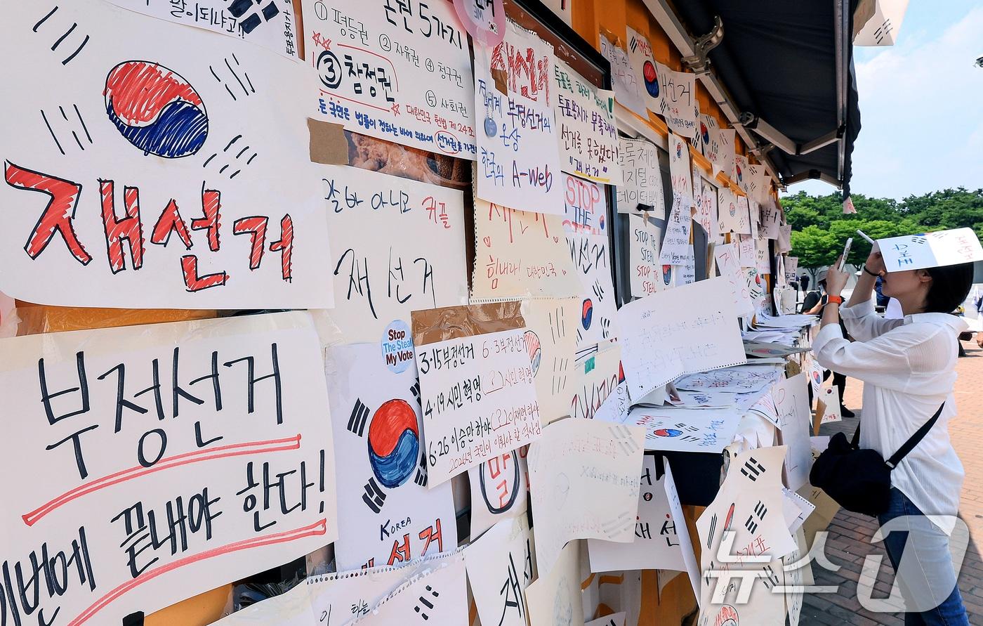 본문 이미지 - 제9회 전국동시지방선거 투표용지 부족 사태를 규탄하며 재선거를 요구하는 집회가 계속되는 10일 서울 송파구 올림픽공원 핸드볼경기장 인근 티켓 부스에 재선거를 요구하는 메시지가 붙어 있다. 2026.6.10 ⓒ 뉴스1 이호윤 기자