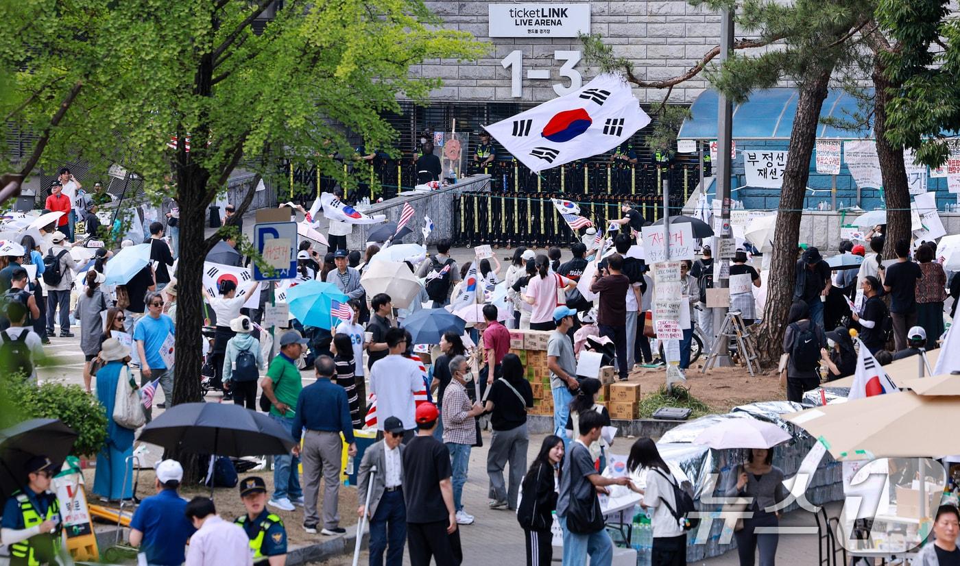 본문 이미지 - 제9회 전국동시지방선거 투표용지 부족 사태를 규탄하며 재선거를 요구하는 집회가 계속되는 10일 서울 송파구 올림픽공원 핸드볼경기장 개표소 앞에 시민들이 모여 재선거를 요구하는 구호를 외치고 있다. 2026.6.10 ⓒ 뉴스1 이호윤 기자